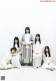 A group of women sitting on the ground in front of a white wall.