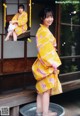 A woman in a yellow kimono standing in a bathtub.