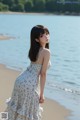 A woman standing on a beach next to the ocean.