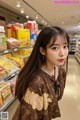 A woman standing in front of a shelf of food.