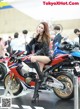 A woman sitting on top of a red and white motorcycle.