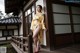 A woman in a yellow kimono leaning against a wall.