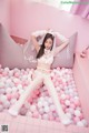 A woman in a white lingerie laying on a bed of pink and white balls.